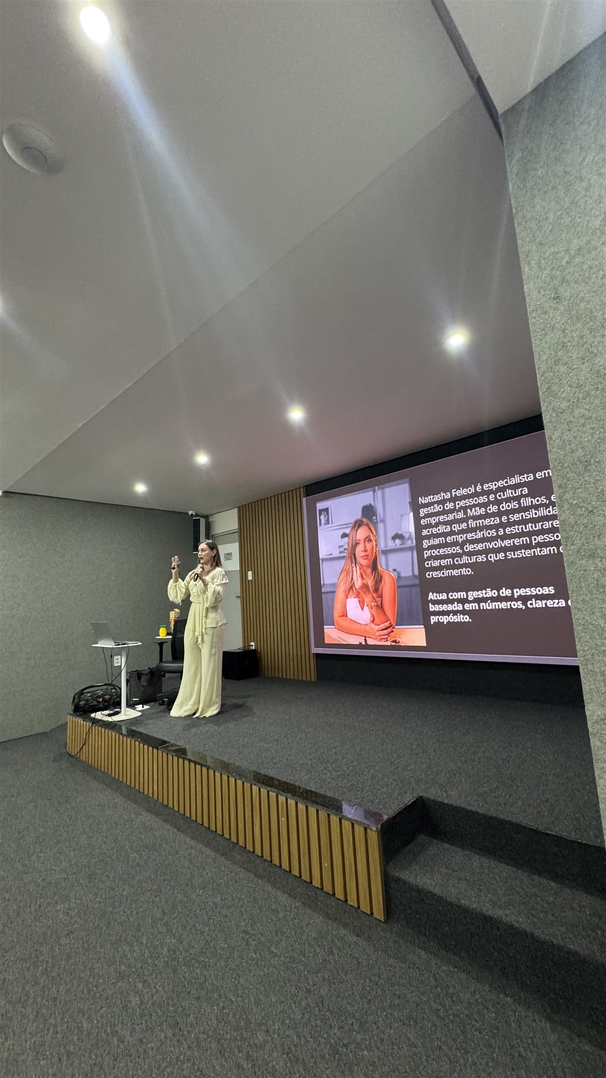 Nattasha Feleol no palco, com slide de apresentação ao fundo